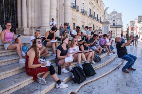 Students sit on steps in Sicily to draw