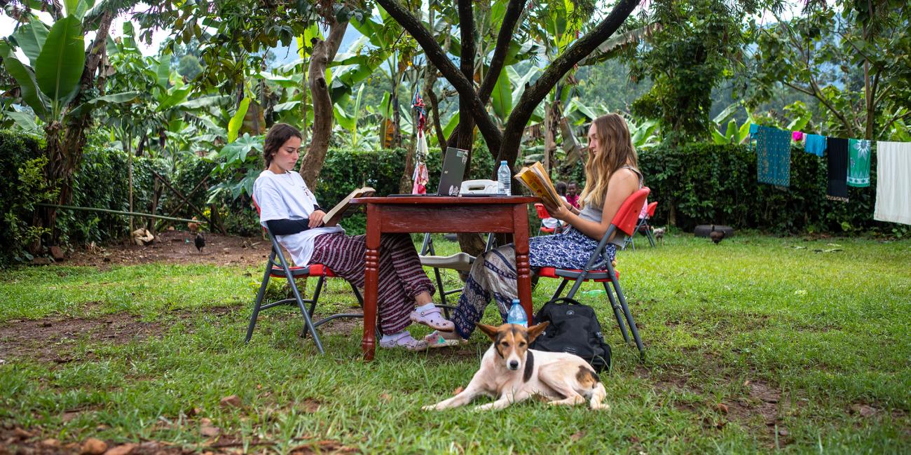 Quinnlyn Burger and Margaux Petruska sit outside at a table at the Zaale homestay in Uganda.